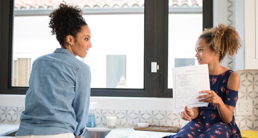 Mother and child in front of a kitchen window with an ADT home security sensor