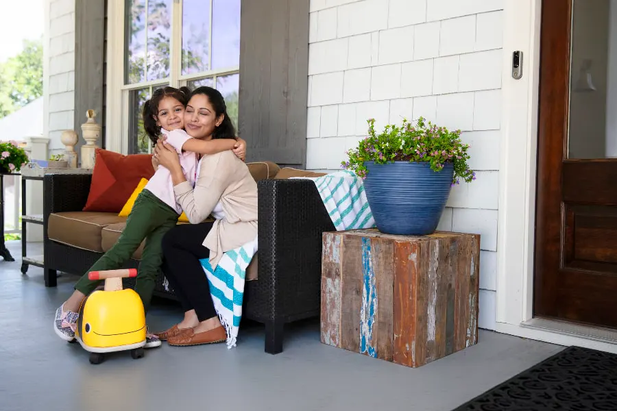 mother and daughter sitting on a porch with a adt doorbell security camera affixed on the door side